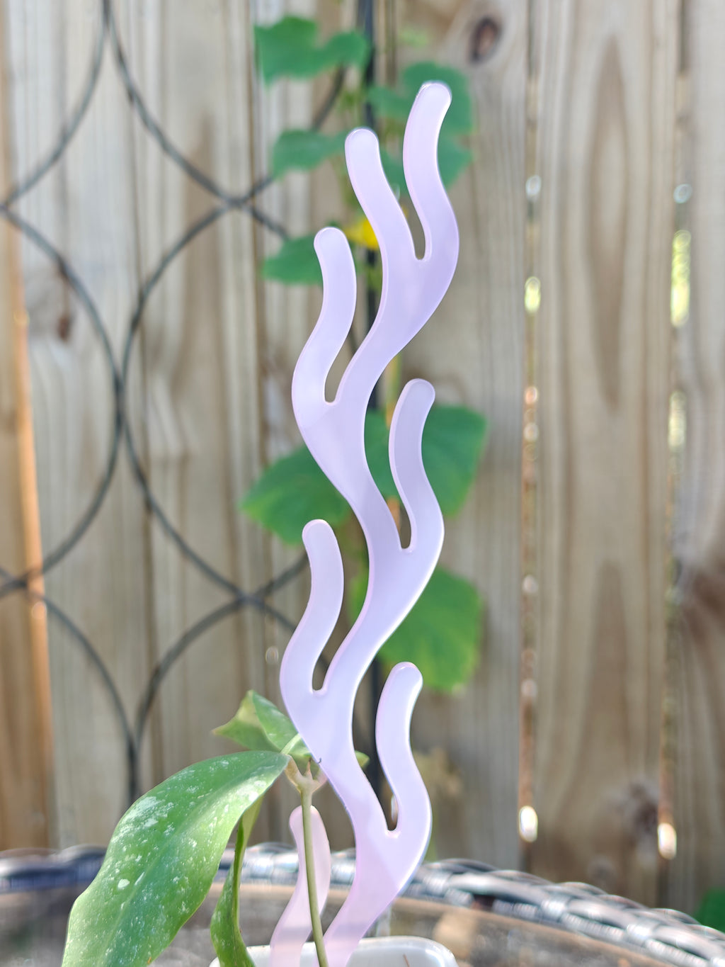 Decorative lavender plant trellis with coral inspired design against a blurred background