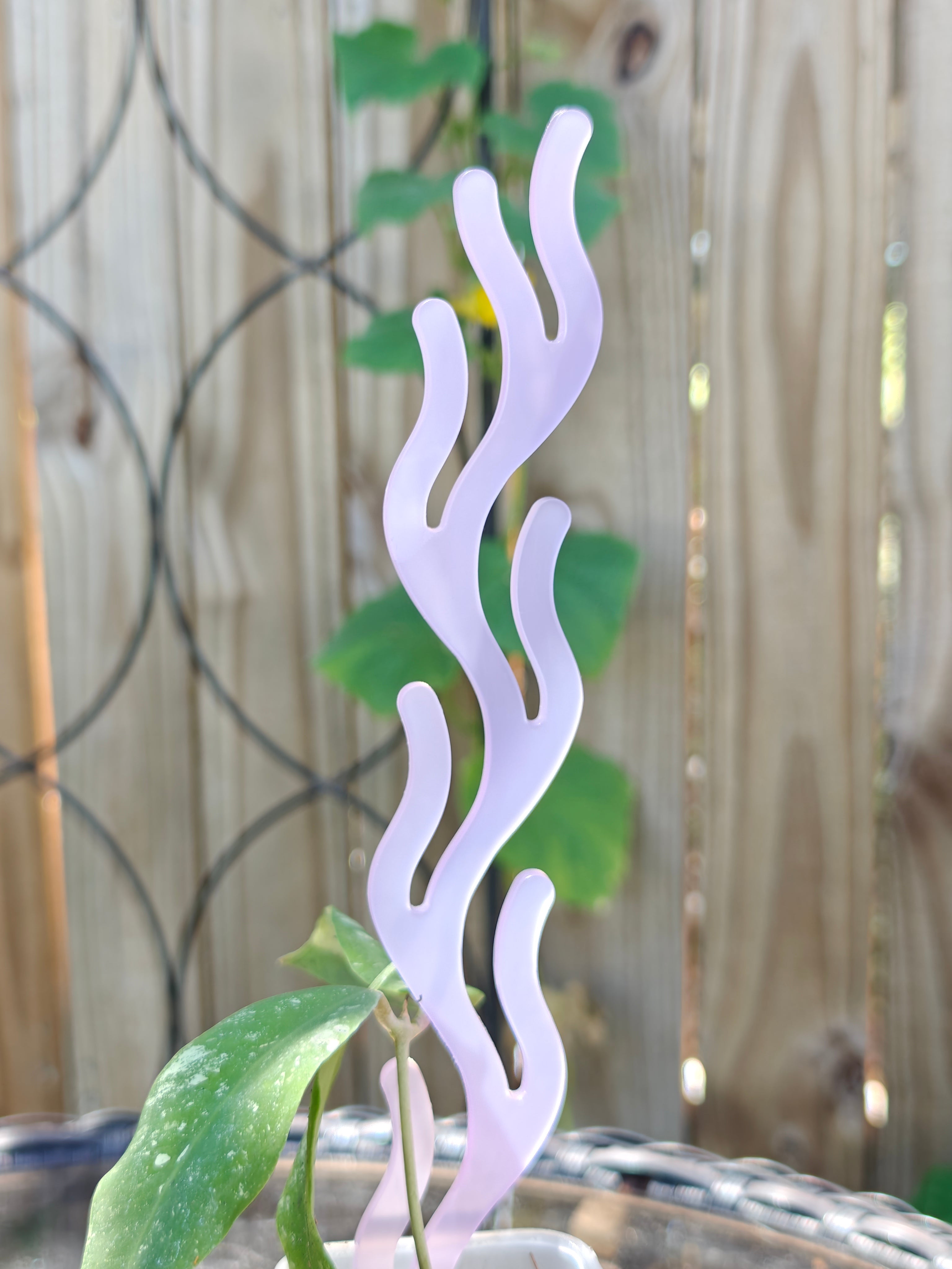 Decorative lavender plant trellis with coral inspired design against a blurred background